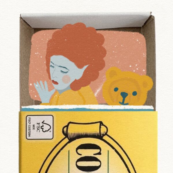 Illustrated red haired sleeping figure on a pink pillow, with teddy bear, in a matchbox